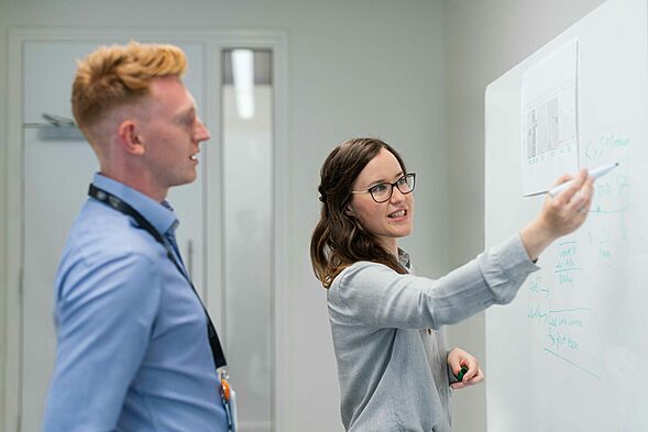 woman in blue long sleeve shirt wearing black framed eyeglasses in Office explaining, office romance, office love