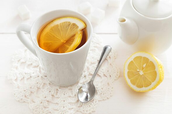 a cup of hot lemon drink with slices and a spoon