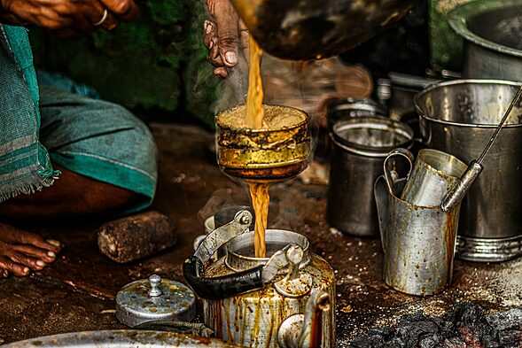 a person pouring chai(Tea) into a pot on a stove