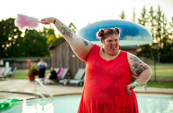 woman in red dress near pool eating sugar candy